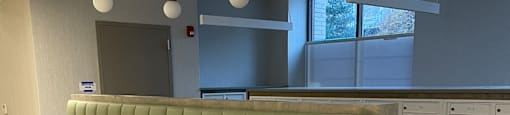 A long green couch with a grey base and a white remote control.