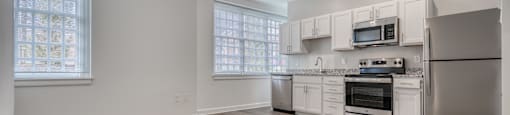 an empty kitchen with white cabinets and stainless steel appliances