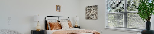 Now leasing senior 1-bedrooms in Baltimore, MD. A bedroom with a bed, chair, and window.