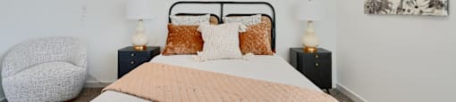 Now leasing senior 1-bedrooms in Baltimore, MD. A bedroom with a large bed and a chair.