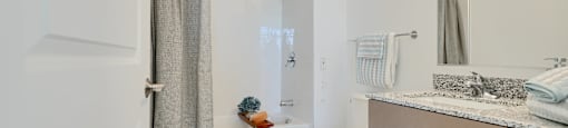 Now leasing senior 1-bedrooms in Baltimore, MD. A white toilet sits in a bathroom with a white shower curtain.