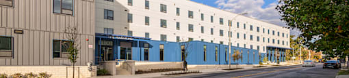A street view of a modern building with a blue awning.