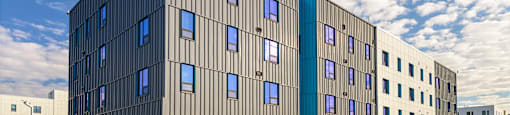 A modern building with a grey facade and blue accent windows.