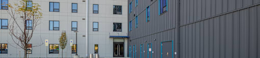 A modern building with a grey facade and blue windows.