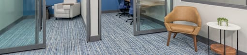 A room with a blue carpet and a brown chair.