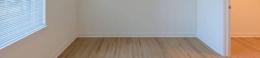 A room with a wooden floor and a door on the right side.