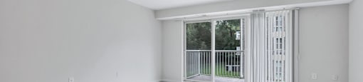 an empty living room with a sliding glass door to a balcony