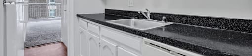 a white kitchen with a sink and white cabinets