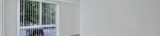 an empty living room with a window and a ceiling fan