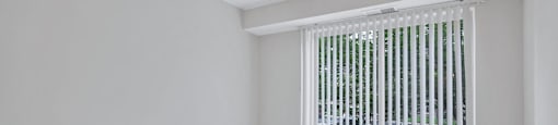 an empty living room with a large window and white walls