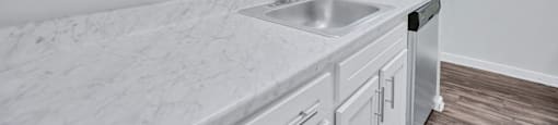 a white kitchen with a sink and white cabinets