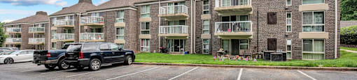 a parking lot in front of an apartment building with two cars parked in front