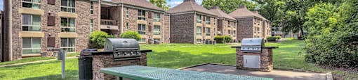 a green picnic table in front of an apartment building with barbecue pits