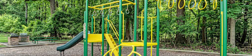 a yellow swing set in a park with trees