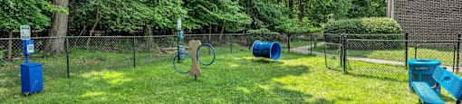 a fenced in dog park with a blue bench and trampoline