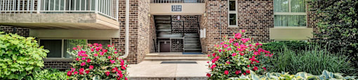 front view of a brick building with plants and flowers