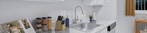 a white kitchen with a sink and white cabinets