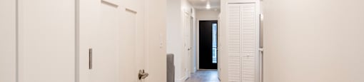 A long hallway with white doors and grey flooring.