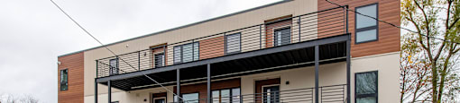 A modern two-story building with a balcony on the second floor.