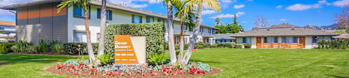 a building with palm trees and a sign in the grass