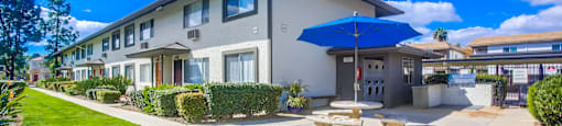 a patio with a table and umbrella outside of a building