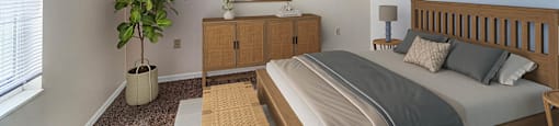A bedroom with a bed, nightstand, and a plant.
