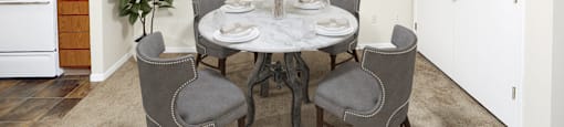 a dining area with a table and chairs and a kitchen in the background