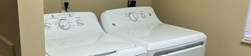 a white washer and dryer in a room with a shelf above it