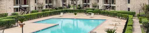 a swimming pool with chairs around it in front of apartments