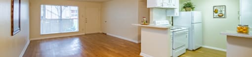 an empty living room and kitchen with a wood floor