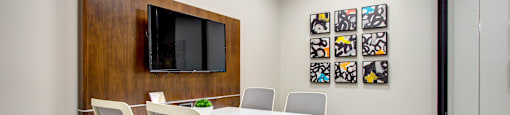 a conference room with a white table and chairs and a television