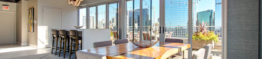 a dining room with a long wooden table and chairs and a view of the city