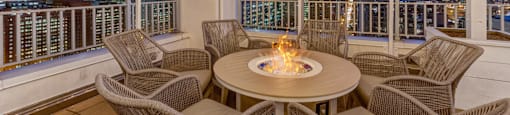 a patio with a fire pit and a view of the city at night
