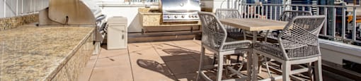 a rooftop patio with a table and chairs and a city in the background