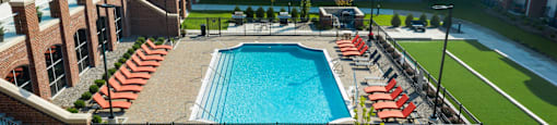Luxury apartments with brick exteriors, outdoor entertainment lounge with grilling stations, luxury swimming pool, poolside lounges, and manicured gardens at Luxembourg Apartments