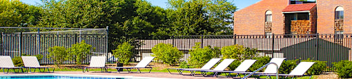 Swimming pool with sundeck, pool-side lounge chairs, and park-like setting at Inwood Apartments in La Vista, Nebraska