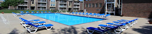 Huge swimming pool with spacious sundeck, poolside lounge chairs, beautiful landscaping, and scenic views at LionsGate Apartments in Lincoln, Nebraska