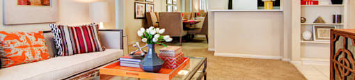 Spacious living room with built-in bookshelves, crown molding, dining room with mirrored accent walls, 9-foot ceilings, and breakfast bar at Tuscany Apartments in Houston.