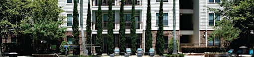 Luxury swimming pool with cabanas, poolside lounges, grilling stations, palm trees and beautiful landscaping at The Voss Apartments in Houston.