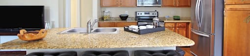 Luxury apartments in Houston with spacious kitchen and dining room with granite countertops, kitchen island, stainless steel appliances, oversized windows, lots of natural light, and hardwood floors.