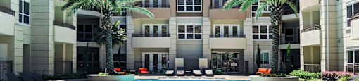 Luxury apartments with resort-style pool and palm trees, fountains, lap lane, and pool-side lounge chairs at Tuscany Walk Apartments in Houston