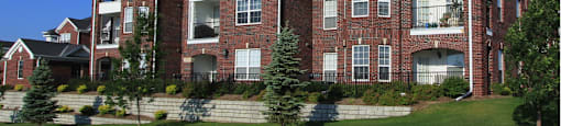 Luxury apartments with spacious balcony, red brick exterior, and beautiful landscaping at Rockledge Oaks Apartments in Lincoln, Nebraska