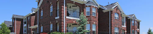 Luxury apartments with spacious balcony, red brick exterior, and beautiful landscaping at Rockledge Oaks Apartments in Lincoln, Nebraska