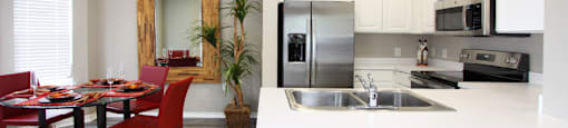 Luxury apartments with spacious u-shaped kitchen, white cabinets, oversized windows, spacious dining room, stainless steel appliances, and bright white kitchen at Rockledge Oaks Apartments in Lincoln, Nebraska
