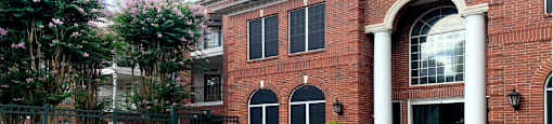 Luxury apartments with brick exteriors and lush landscaping at Tuscany Apartments in Houston.