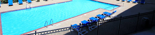 Apartments with large swimming pool, spacious sundeck, lots of poolside lounge chairs, and scenic views at Tanglewood Apartments in Lincoln, Nebraska