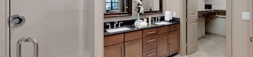 Luxury apartments with spacious master bathroom with oval soaking tub, separate shower with glass enclosure, and double sink with granite slab vanity top at Tuscany Walk Apartments in Houston.