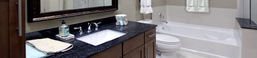 Luxury bathroom with oval soaking tub, glass shower, granite countertops and linen closet at Bellemeade Apartments in west Des Moines