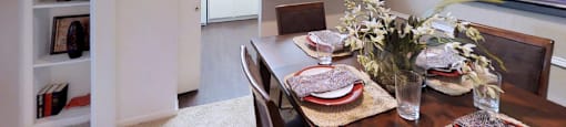 Spacious dining room with built-in bookshelf, bright kitchen with white cabinets, and breakfast bar at Woodlake Oaks Apartments in Houston