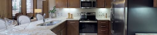 Luxury apartments with spacious kitchen and built-in wine rack, granite countertops, kitchen island, stainless steel appliances, and designer tile backsplash at Tuscany Walk Apartments in Houston Texas.